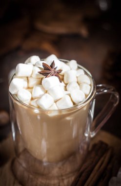 Hot coffee with milk in a glass with double walls with marshmallow and anise star. Brown, Selective focus