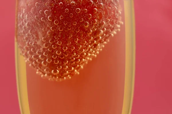 Strawberry in champagne stock images. Glass of champagne with strawberry. Champagne on a pink background with copy space for text. Festive red background. Valentines Day concept