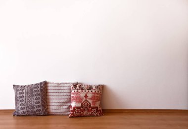 Oturma odasındaki boş beyaz duvar. Ahşap zemin üzerindeki dekoratif yastıklar. Boş oda stoğundaki fotoğraf görüntüleri. Metin için kopyalama alanı olan yastıklı oda