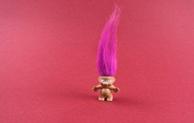 Pembe saçlı, klasik oyuncak resimli bir Trol. Kırmızı arkaplanda pembe tüylü bir elf resmi. Pembe kıllı trol figürü eski oyuncak resimleri