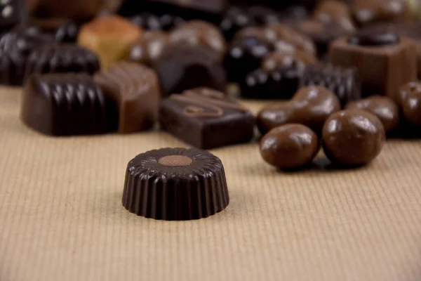 チョコレートは 茶色の背景ストック画像上のプリリン チョコレートは テキストストック画像のためのコピースペースを持つ茶色の背景にプリライン 様々なチョコレートキャンディフレーム — ストック写真