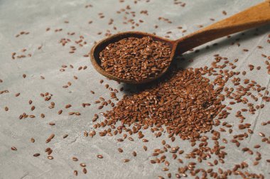 Gri arka planda eski ahşap kaşık keten tohumu. Sağlıklı yemek..