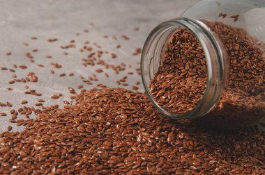 Cam kavanoz keten tohumlar üzerinde gri bir arka plan ile. Sağlıklı gıda.