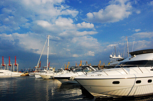 White yacht in the harbor. Beautiful reflection in the blue calm water. Summer.