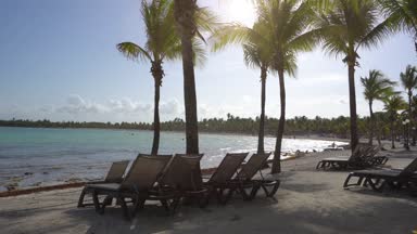 Tropik sahil lüks resort otel beach adlı görüntüleyin. Hindistan cevizi avuç içi rüzgara karşı mavi gökyüzü içinde çırpınan yaprakları. Karayip Denizi'nin turkuaz su. Riviera Maya Meksika.