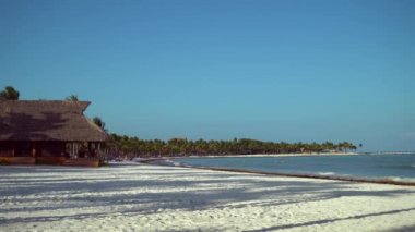 Tropik sahil lüks resort otel beach adlı görüntüleyin. Hindistan cevizi avuç içi rüzgara karşı mavi gökyüzü içinde çırpınan yaprakları. Karayip Denizi'nin turkuaz su. Riviera Maya Meksika.