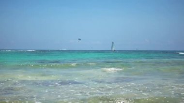 Tropikal plaj manzarası. Turistler ile paraşüt paraşüt tekne yolculuğu. Yelkenli Yat dalgalar üzerinde yola çıkacak. Turkuaz su Karayip Denizi. Riviera Maya Meksika