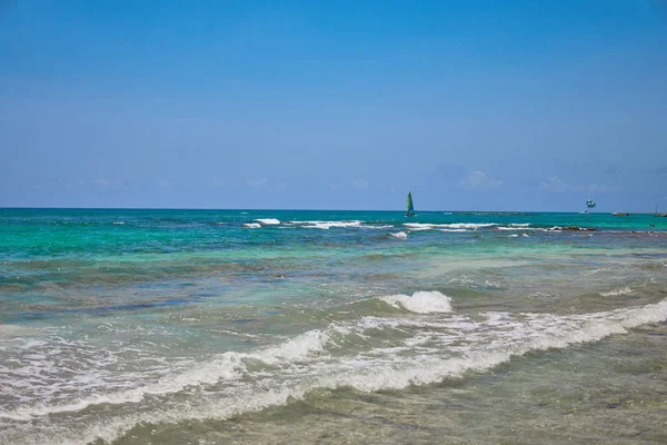 Vue sur la plage tropicale. Les touristes font du parachute sur un bateau à voile. Voile yacht navigue sur les vagues. Eau turquoise de la mer des Caraïbes. Riviera Maya Mexique — Photo