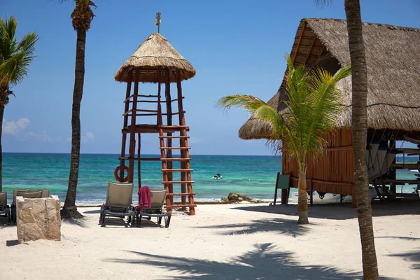 View at luxury resort hotel beach of tropical coast. Place of lifeguard. Leaves of coconut palms fluttering in wind against blue sky. Turquoise water of Caribbean Sea. Riviera Maya Mexico — Stock Photo, Image