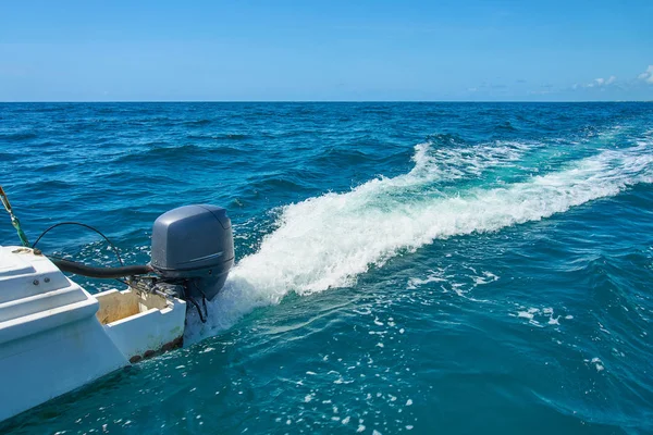 Sentier sur la surface de l'eau derrière le catamaran à moteur en mouvement rapide dans la mer des Caraïbes Cancun Mexique. Journée ensoleillée d'été, ciel bleu nuageux Photo De Stock