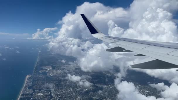 Volando sobre Miami. Vista de la costa este desde la ventana de los aviones. Hermosas nubes blancas contra el cielo azul. Las aguas turquesas de la costa atlántica. — Vídeo de stock
