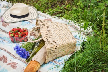 Sepet, ekmek, çiçekler, çilek ile çimlerde piknik ayarı