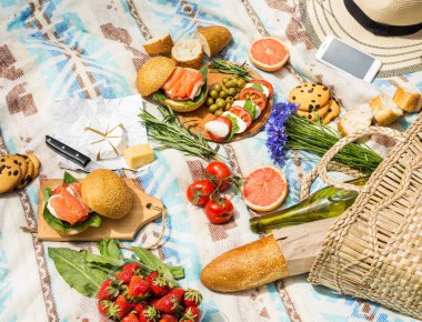 Sepet, sandviç, meyve, çilek, salata ve zeytin ile çimlerde piknik ayarı.