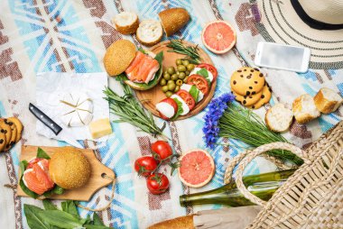 Piknik sepeti, sandviç, meyve, çilek, salata ve zeytin ile çim ayarda. Üstten görünüm