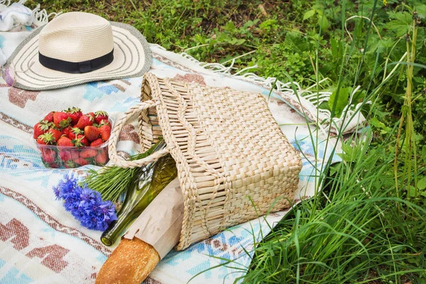 Sepet, ekmek, çiçekler, çilek ile çimlerde piknik ayarı