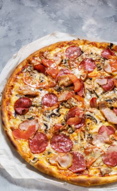 Rustik beton zemin üzerine pepperoni, jambon, peynir ve domates soslu taze ev yapımı pizza.