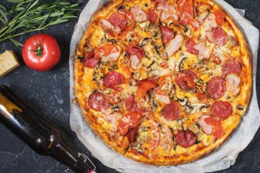 Biberli, jambon, peynir ve şişe bira rustik taş zemin üzerine taze ev yapımı pizza. Üstten görünüm