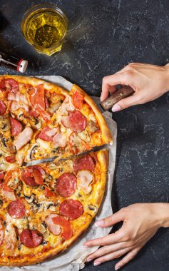 Eller bir parça taze ev yapımı pizza sucuk, salam, peynir rustik taş zemin üzerine tutun. Üstten görünüm