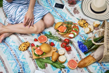 Sepet, sandviç, meyve, çilek, salata ve zeytin ile çimlerde piknik ayarı