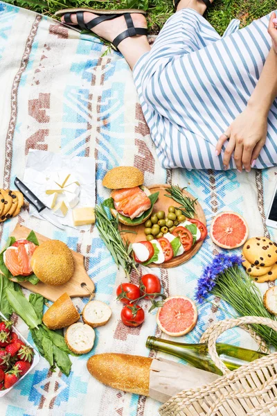 Sepet, sandviç, meyve, çilek, salata ve zeytin ile çimlerde piknik ayarı
