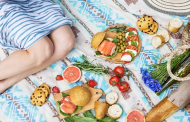 Sepet, sandviç, meyve, çilek, salata ve zeytin ile çimlerde piknik ayarı.