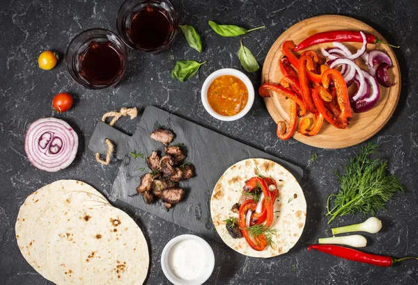 Taze lezzetli Meksika tacos ve gıda maddeleri siyah taş zemin üzerine. Yemek. Üstten görünüm
