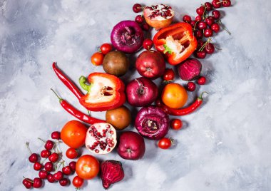 Beton zemin üzerine, üstten görünüm sağlıklı yemek için taze malzemelerle çiğ kırmızı organik sebze. Vegan veya diyet gıda kavramı