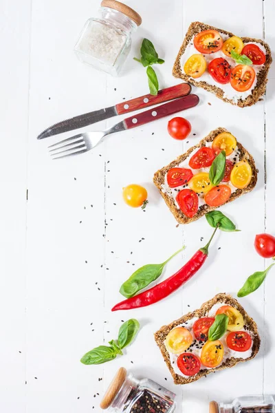 Krem peynir, domates ve fesleğen beyaz tahta masada sandviç