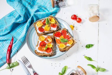 Krem peynir, domates ve fesleğen beyaz tahta masada sandviç.