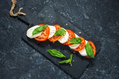 Caprese salatası. Taş masa üzerinde mozzarella peyniri, domates ve fesleğen bitki yaprakları