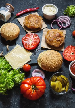 Yemek hamburger için malzemeler. Izgara tavuk patty, çörekler, soğan, domates, turşu, siyah arka plan üzerinde peynir sos
