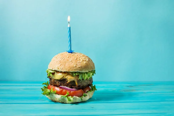 Ev yapımı Hamburger Barbekü sığır eti ve mavi arka plan üzerinde Doğum günü partisi için yanan mum ile sandviç. Konsept tatil.