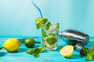 Mojito kokteyl limon ve nane highball cam ahşap bir masa üzerinde. Mavi arka plan.