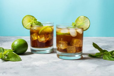ROM ve kola. Cuba Libre içki kireç ve rustik beton masada buz ile.