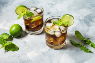 ROM ve kola. Cuba Libre içki kireç ve rustik beton masada buz ile.