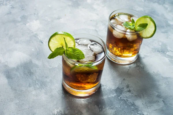 ROM ve cola Cuba Libre içki kireç ve rustik beton masada buz ile