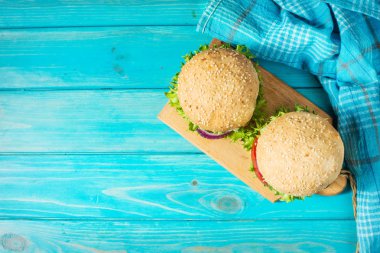 Sığır eti, domates, peynir mavi ahşap zemin üzerine lezzetli ızgara ev yapımı hamburger. En iyi görünüm ve kopya alanı