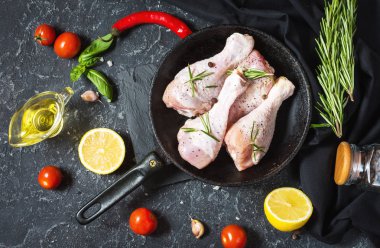 Ham pişmemiş tavuk budu, taş kurulu, et yemek pişirmek için malzemelerle sopaları. Üstten görünüm