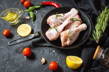 Çiğ çiğ tavuk budu, sopaları taş kurulu, et yemek pişirmek için malzemelerle.