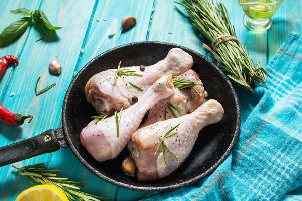 Çiğ çiğ tavuk budu, ızgara et yemek pişirmek için malzemelerle mavi ahşap arka plan üzerinde.