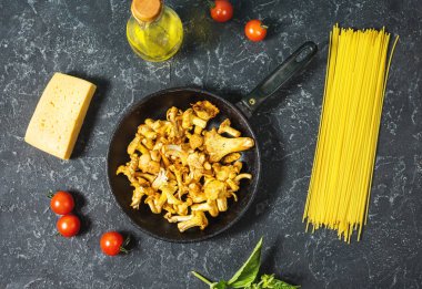 Pişmemiş makarna ve Cantharellus cibarius taş koyu arka plan üzerinde mantar. Üstten görünüm.