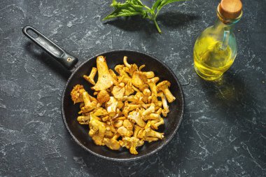 Bir tavada bir siyah taş tablo taze Cantharellus cibarius mantar.