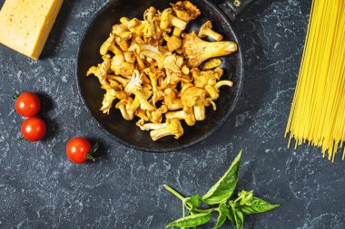 Pişmemiş makarna ve Cantharellus cibarius taş koyu arka plan üzerinde mantar. Üstten görünüm.