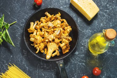 Pişmemiş makarna ve Cantharellus cibarius taş koyu arka plan üzerinde mantar. Üstten görünüm.