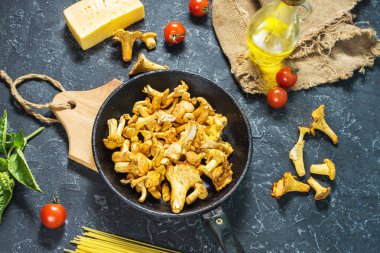 Karanlık taş arka plan üzerinde pişmemiş makarna ve Cantharellus cibarius mantar