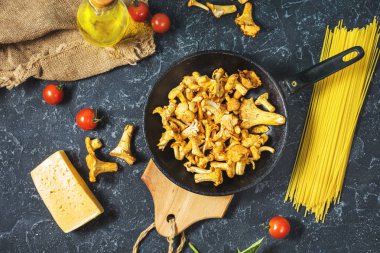 Pişmemiş makarna ve Cantharellus cibarius taş koyu arka plan üzerinde mantar. Üstten görünüm.
