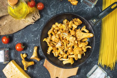 Pişmemiş makarna ve Cantharellus cibarius taş koyu arka plan üzerinde mantar. Üstten görünüm.