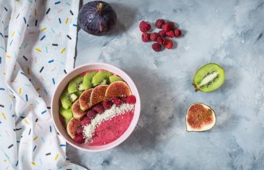 İncir, kivi ve beton zemin üzerine Hindistan cevizi ile ahududu güler yüzlü kase. Üstten görünüm