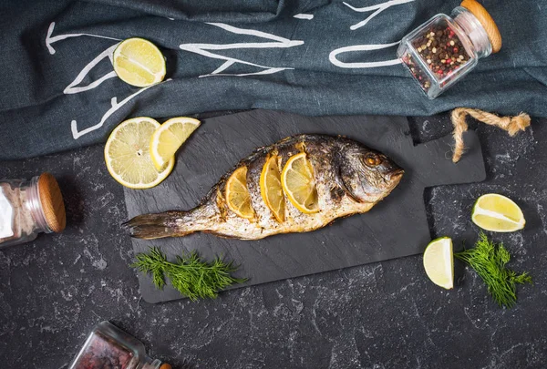 Жареная Рыба Каменной Тарелке Лимоном Темном Фоне Вид Сверху — стоковое фото