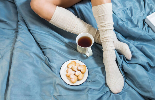 Woman in cozy home wear relaxing at home and drinking tea. Top view